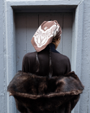 Woman wearing an oversized paisley cotton headscarf and fur stole standing in a doorway.